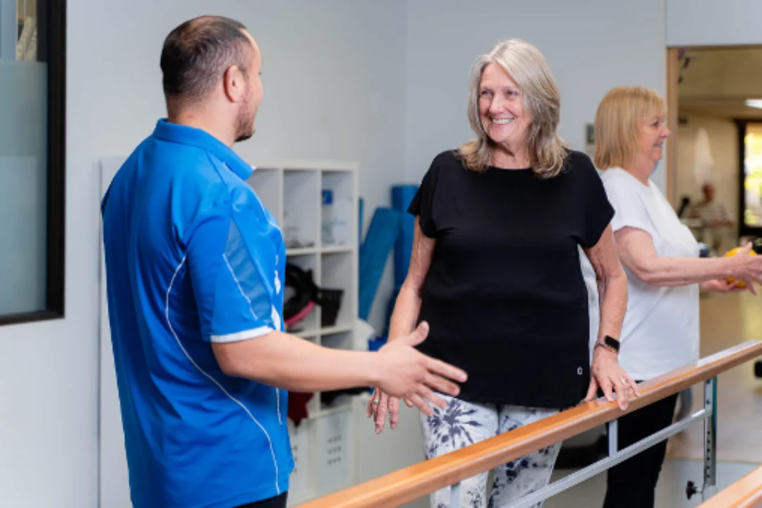 A staff member greets a smiling client during a wellness session, reflecting the everyday care and connection ECH staff bring to their work.